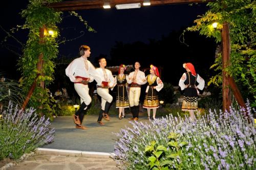 a group of people in traditional dress dancing in a garden at Motel Hanat in St. St. Constantine and Helena