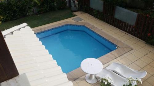 a swimming pool with two white chairs and a table and a white table and chairs at Casa proxima ao mar em Guarajuba in Avaré