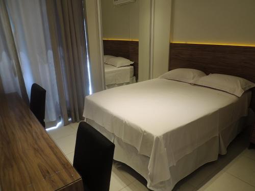 a bedroom with a large white bed and a mirror at Liberty - CA - Lago Norte in Brasília