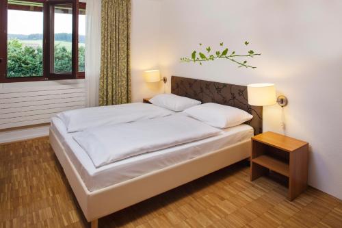 1 dormitorio con 1 cama blanca, mesa y ventana en Hapimag Ferienwohnungen Unterkirnach, en Unterkirnach