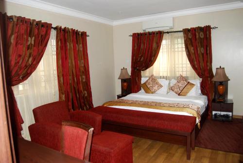 a bedroom with a bed with red curtains and a chair at Grand Inn & Suites in Ijebu Ode