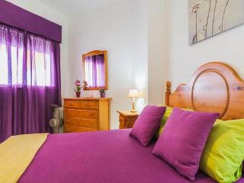 a bedroom with a purple bed with purple and yellow pillows at Apartamento Pepi Chipiona in Chipiona