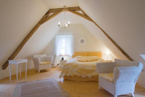 a bedroom with a bed and chairs in a attic at La Tuilerie du Paligny in Tallud-Sainte-Gemme