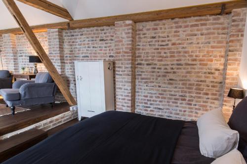 ein Schlafzimmer mit einer Ziegelwand, einem Bett und einem Stuhl in der Unterkunft Room 68 in Friedberg