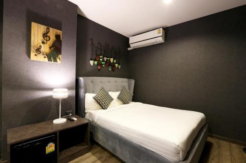 a small bedroom with a bed with a white bedspread at The Printing House Poshtel in Bangkok