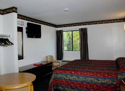 ein Hotelzimmer mit einem Bett und einem Tisch in der Unterkunft Home Style Inn in Manassas