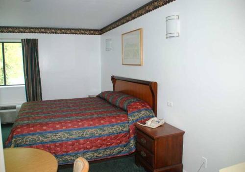 a bedroom with a bed and a table with a phone at Home Style Inn in Manassas