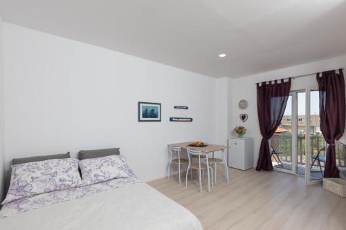 a bedroom with a bed and a table with chairs at Apartman Rokolj in Cavtat