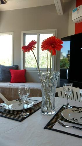 a vase with red flowers sitting on top of a table at Cabaña Loft La Ribera in Maipú