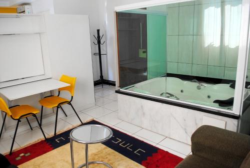 a bathroom with a tub and a table and chairs at Hotel 1000 in Piracicaba