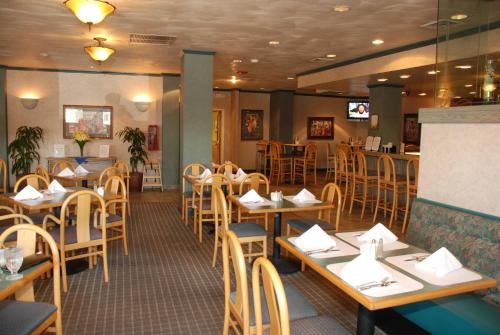a dining room with tables and chairs in a restaurant at Oakland Airport Executive Hotel in Oakland