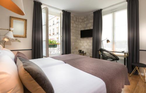 una camera d'albergo con letto e finestra di Hôtel Jeanne d'Arc Le Marais a Parigi