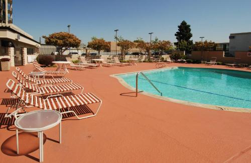 a group of lounge chairs and a swimming pool at Oakland Airport Executive Hotel in Oakland