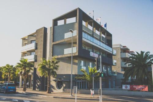 a tall building with palm trees in front of it at Best Western Plus Antibes Riviera in Antibes
