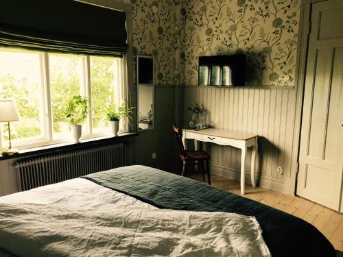 a bedroom with a bed and a desk and a window at Villamilsten B&B in Lidköping