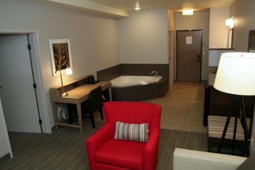 a living room with a red chair and a tub at Country Inn & Suites by Radisson, Prineville, OR in Prineville