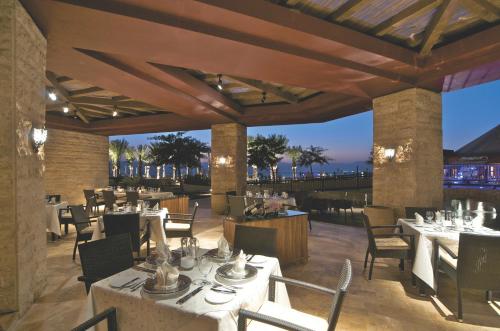 a restaurant with white tables and chairs on a patio at Mövenpick Resort & Spa Tala Bay Aqaba in Aqaba