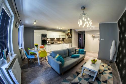 a living room with a blue couch and a kitchen at Apartamenty Centrum in Koszalin