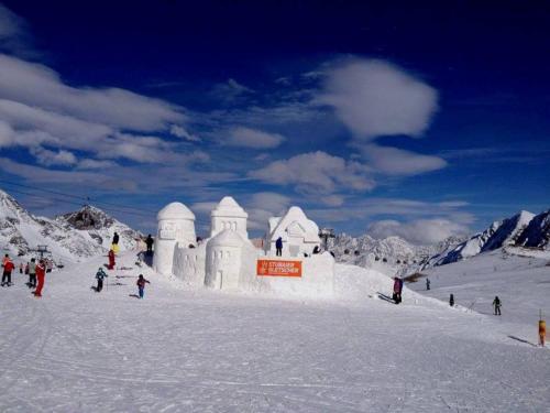 a group of people standing around an ice house in the snow at Apart- Chalet GletscherGlück in Telfes im Stubai