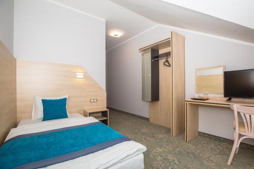 a bedroom with a bed and a desk and a tv at Hotel Vela in Tczew