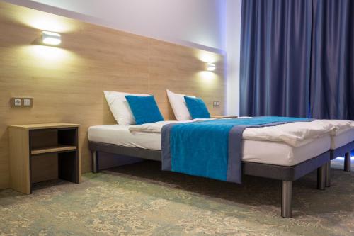 a bedroom with a bed with blue and white pillows at Hotel Vela in Tczew
