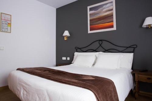 a bedroom with a white bed with a blanket on it at Hotel Bruna in Esterri d'Àneu