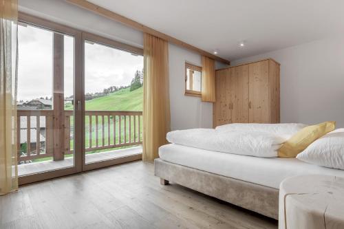 a bedroom with two beds and a balcony at Ciasa de Lenz in San Cassiano