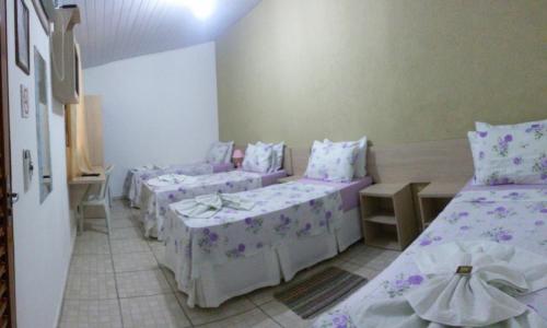 a room with four beds with purple sheets and pillows at Pousada Jubaia in Bonito