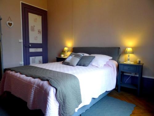 a bedroom with a large bed with two tables and two lamps at L'Ajoussienne in Ajou