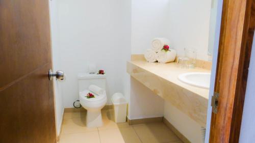 a white bathroom with a toilet and a sink at Costa Alegre Hotel & Suites in Rincon de Guayabitos