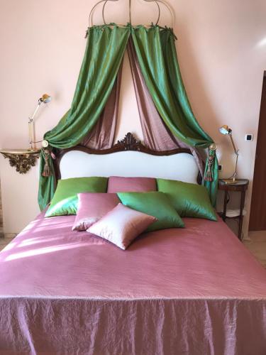 a bed with a canopy with pillows on it at Villa Ottolenghi Wedekind in Acqui Terme