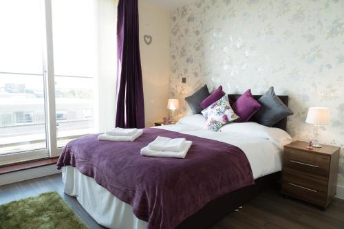 - une chambre avec un lit doté de draps violets et une fenêtre dans l'établissement Modern Penthouse, 2 mins walk from Cambridge Station, lift access, secured gated on-site parking, self check-in, SUPER Fast WIFI, Terrace & Sleeps 6, à Cambridge