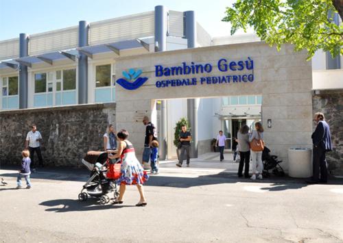 une femme poussant une poussette devant un bâtiment dans l'établissement Residenza Fermi, à Rome