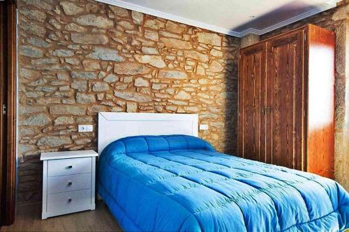 セーにあるCasa Cascada do Ezaroの青いベッドと石の壁が備わるベッドルーム1室が備わります。