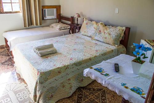 a bedroom with two beds and a table at Pousada Lagomar da Barra de Marica in Maricá