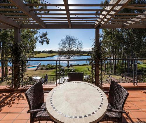 a table and chairs on a patio with a view of a lake at Oaks Cypress Lakes Resort in Pokolbin