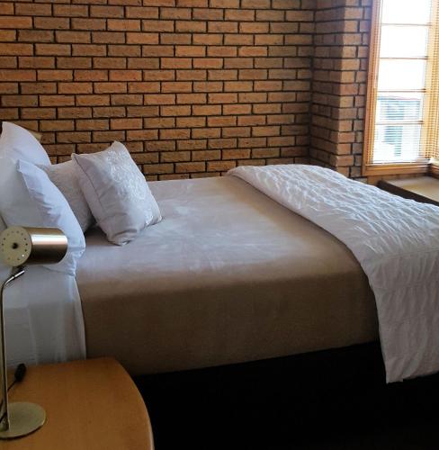 a bed in a bedroom with a brick wall at Stanley Village Waterfront Accommodation in Stanley