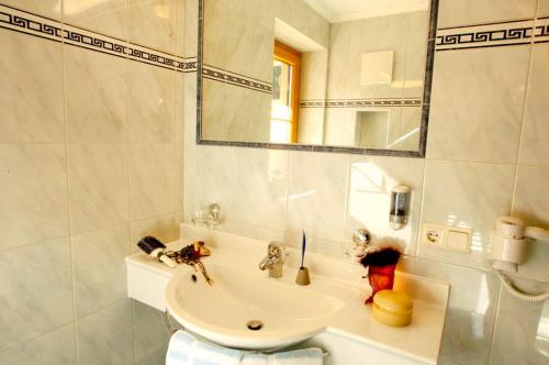 Baño blanco con lavabo y espejo en Hotel Garni Forelle, en Tux