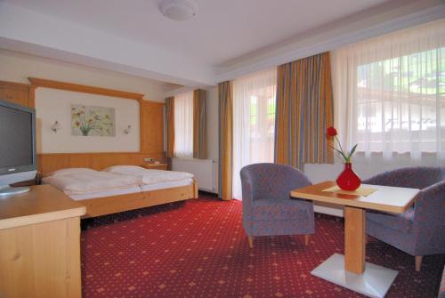 a hotel room with a bed and a table and chairs at Hotel Garni Forelle in Tux