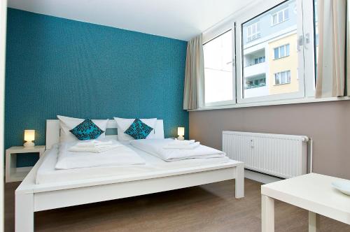a bedroom with a white bed with a blue wall at Apartmenthouse Berlin - Am Görlitzer Park in Berlin