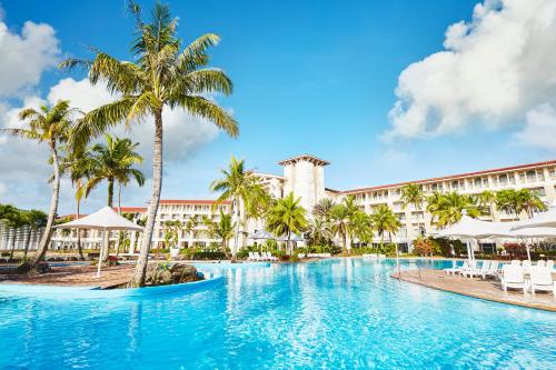 a swimming pool in front of a resort with palm trees at LeoPalace Resort Guam in Yona