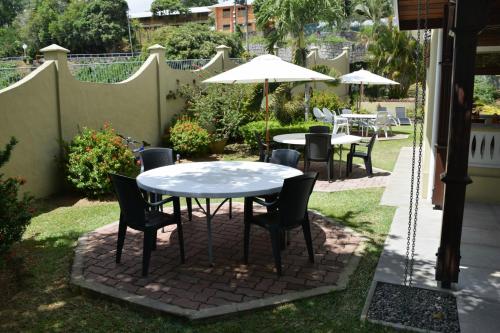 a patio with tables and chairs and an umbrella at Bel Air Hotel in Victoria
