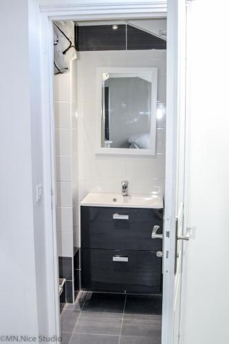 une salle de bain avec un lavabo et un miroir dans l'établissement Beau Studio Nice, à Nice