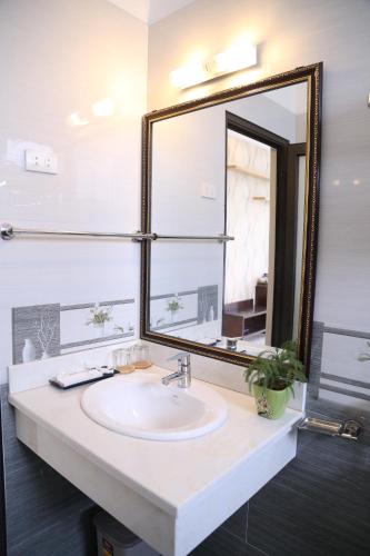 baño con lavabo y espejo grande en Iris Hotel, en Ha Long
