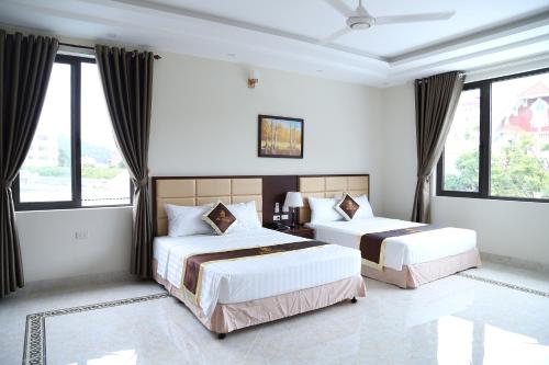 two beds in a room with large windows at Iris Hotel in Ha Long