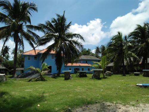 a blue house with palm trees in front of it at Happy Days Resort in Ko Mak