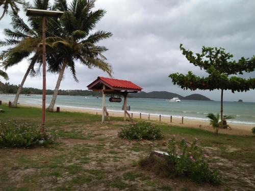 a beach with a hut and palm trees and the ocean at Happy Days Resort in Ko Mak