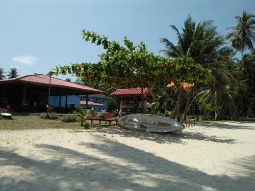 a boat sitting on the beach next to a building at Happy Days Resort in Ko Mak