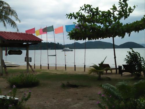 a group of flags on a beach with a boat in the water at Happy Days Resort in Ko Mak
