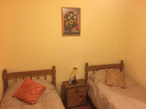 a bedroom with two beds and a night stand and a picture at Hostal Playa Herradura in Coquimbo